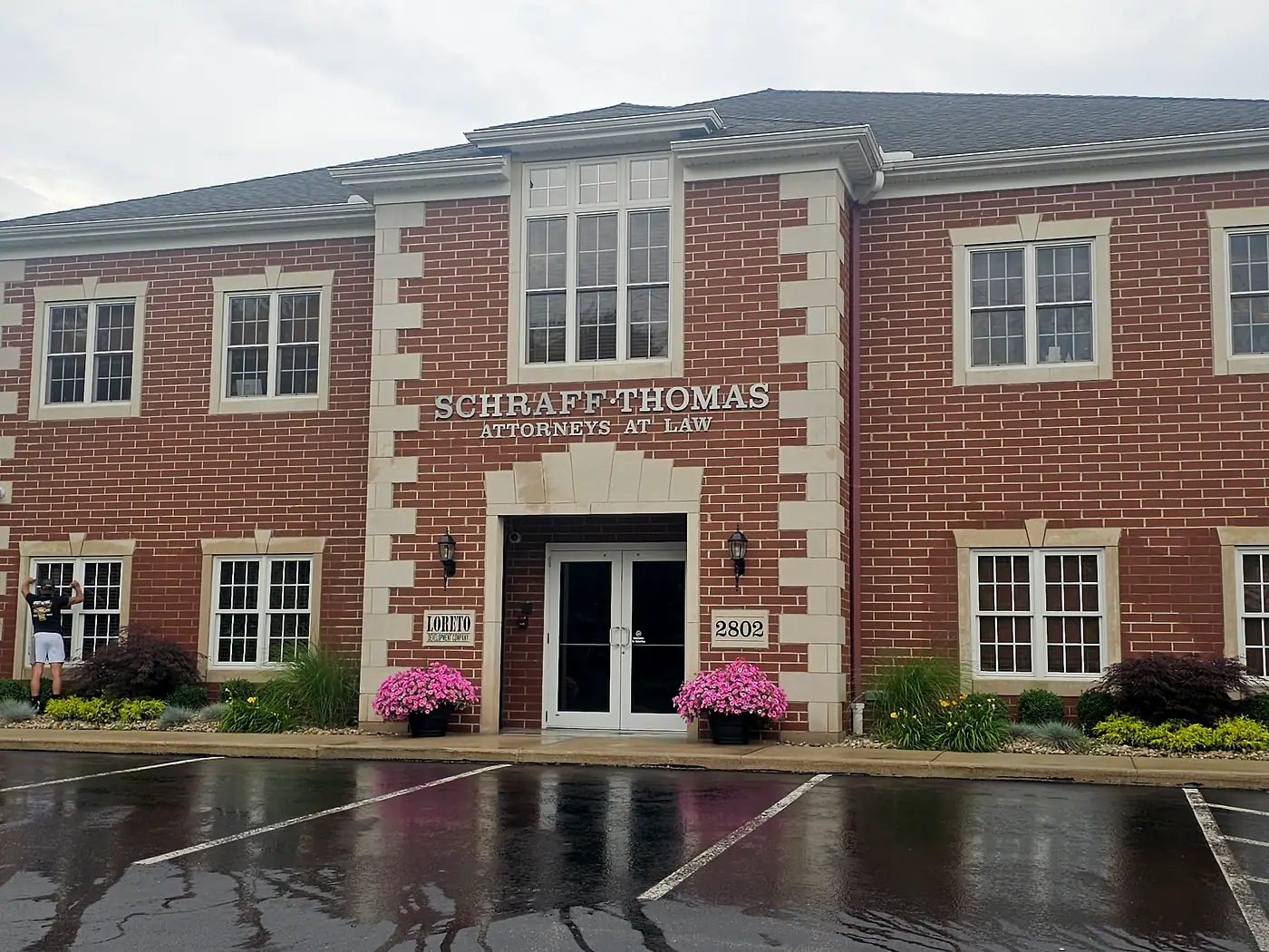 Two-story brick office building with a freshly washed entrance and parking lot