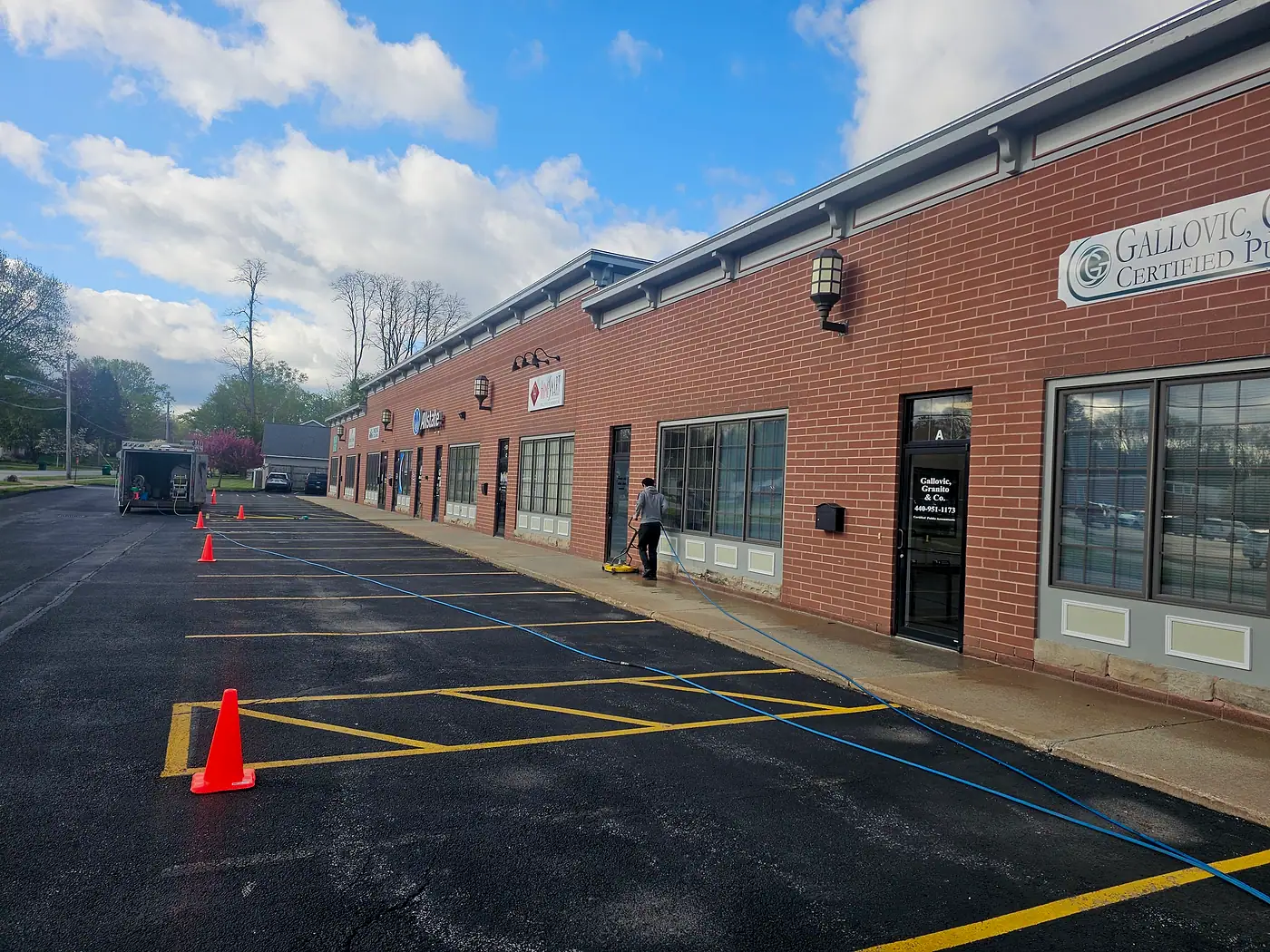 Long brick storefront row with a wet, freshly washed parking lot
