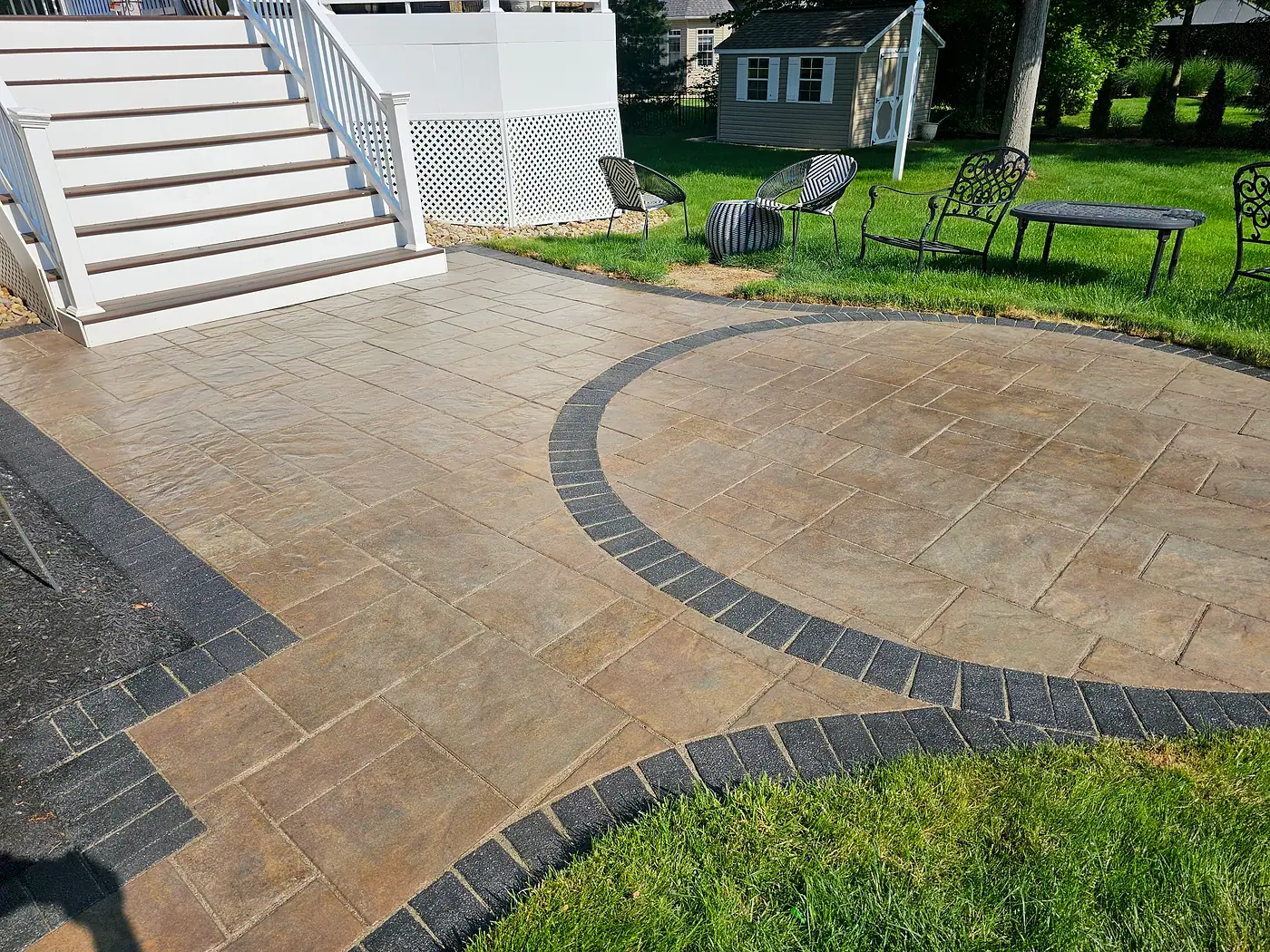 Stamped concrete patio with a dark border and a circular design beside white steps