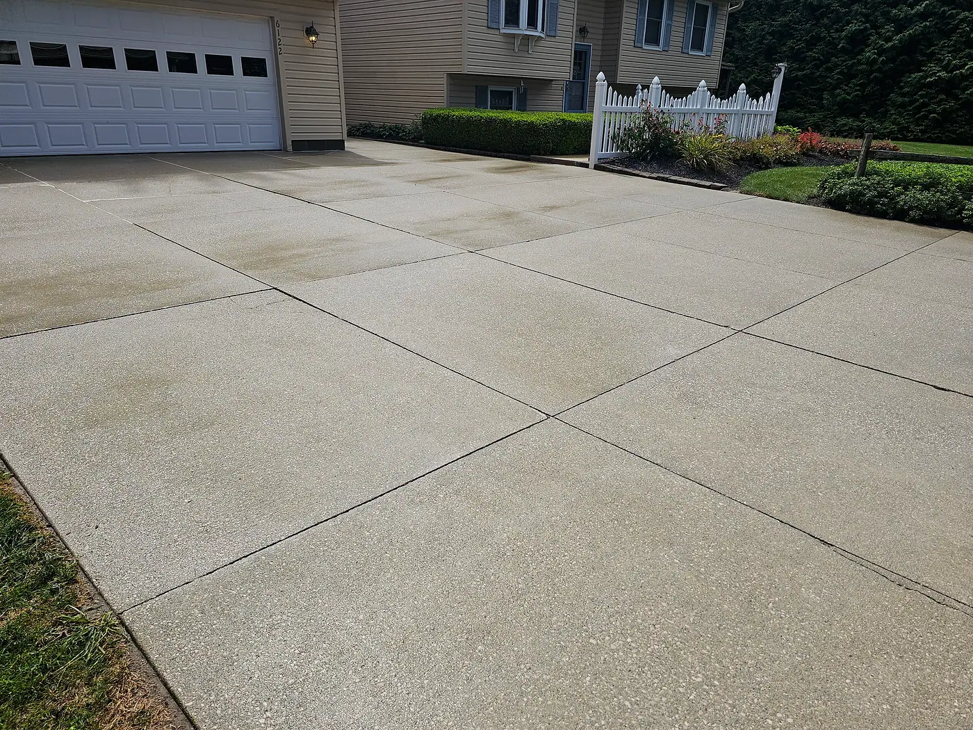 Clean light concrete driveway beside a garage