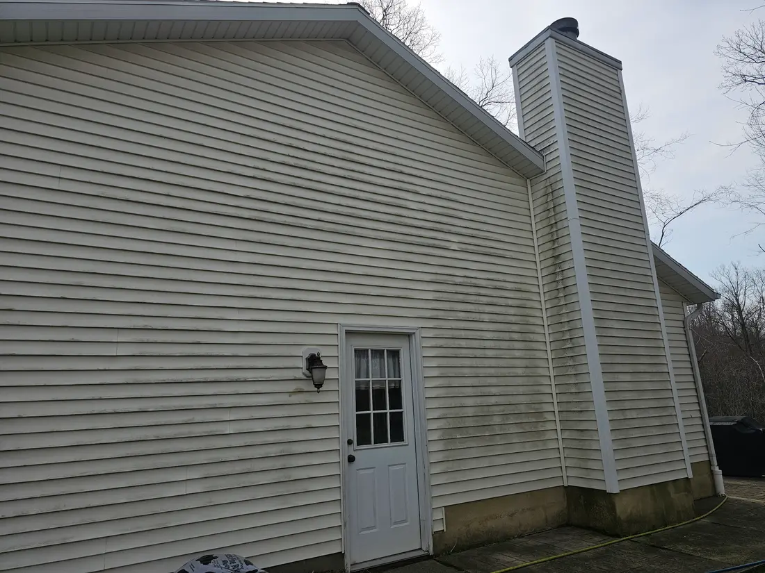 Before: Green-streaked siding beside a chimney before and after washing