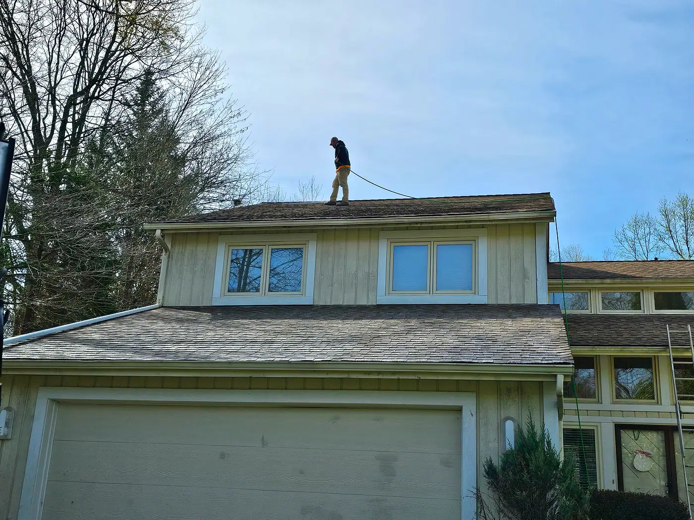 Worker on the roof of a two-story house above the garage
