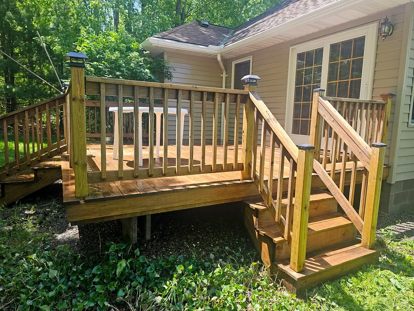 Wood deck with railings and steps, wet from cleaning, beside a tan house in Chesterland