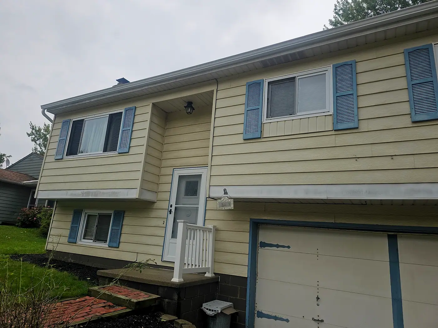 Home with cream siding, blue shutters, and a white porch railing in Painesville