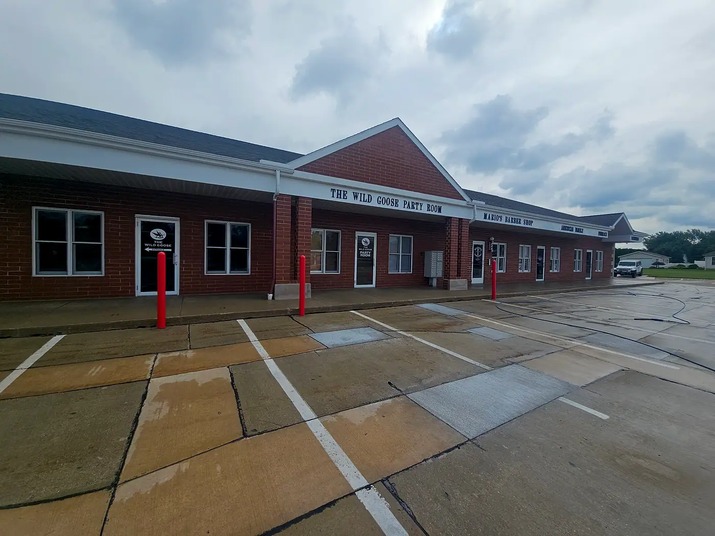 Brick plaza storefronts with a concrete parking area and sidewalk being washed in Perry